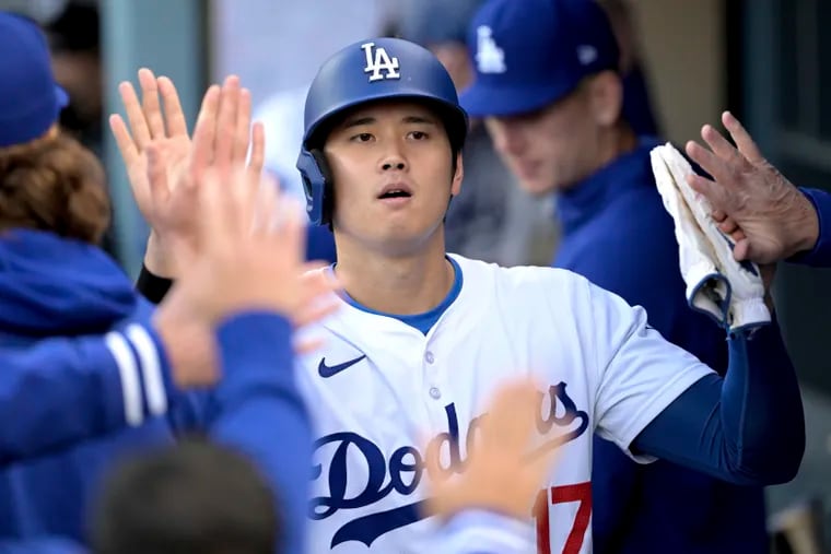 Los Angeles Dodgers Shohei Ohtani is greeted in the dugout after scoring against the St. Louis Cardinals during the sixth inning of a baseball game Sunday, March 31, 2024, in Los Angeles. (AP Photo/Jayne-Kamin-Oncea)